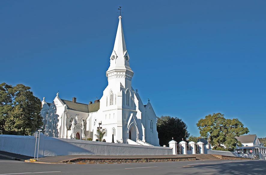 designer pool covers A white church with a steeple in the middle of a street, adorned with beautiful pool covers.