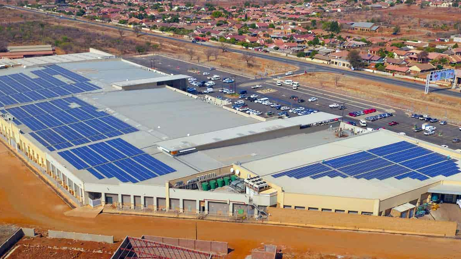 designer pool covers An aerial view of a building with solar panels on the roof, also featuring pool covers.