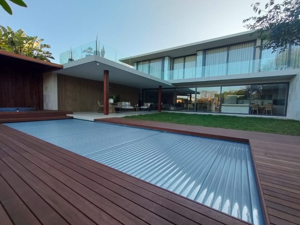 designer pool covers A house featuring a wooden deck and a swimming pool, with tips on how to keep cats off the pool cover.
