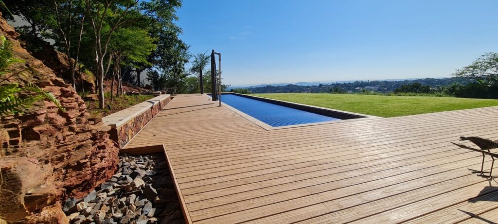 designer pool covers A wooden deck with a swimming pool in the background.