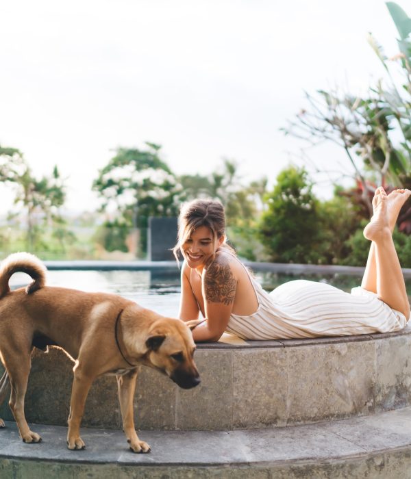 Young woman resting with dog on swimming pool edge